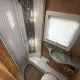 Salle de bain compacte de camping-car avec douche, lavabo et toilettes.