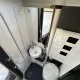 Salle de bain compacte avec douche, lavabo et toilettes dans un camping-car moderne.