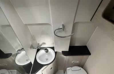 Salle de bain compacte avec lavabo, toilettes et douche dans un espace restreint.