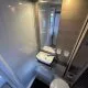Salle de bain compacte avec lavabo, miroir et toilettes dans un camping-car moderne.