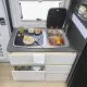 Cuisine compacte de camping-car avec évier, planche à découper et fruits