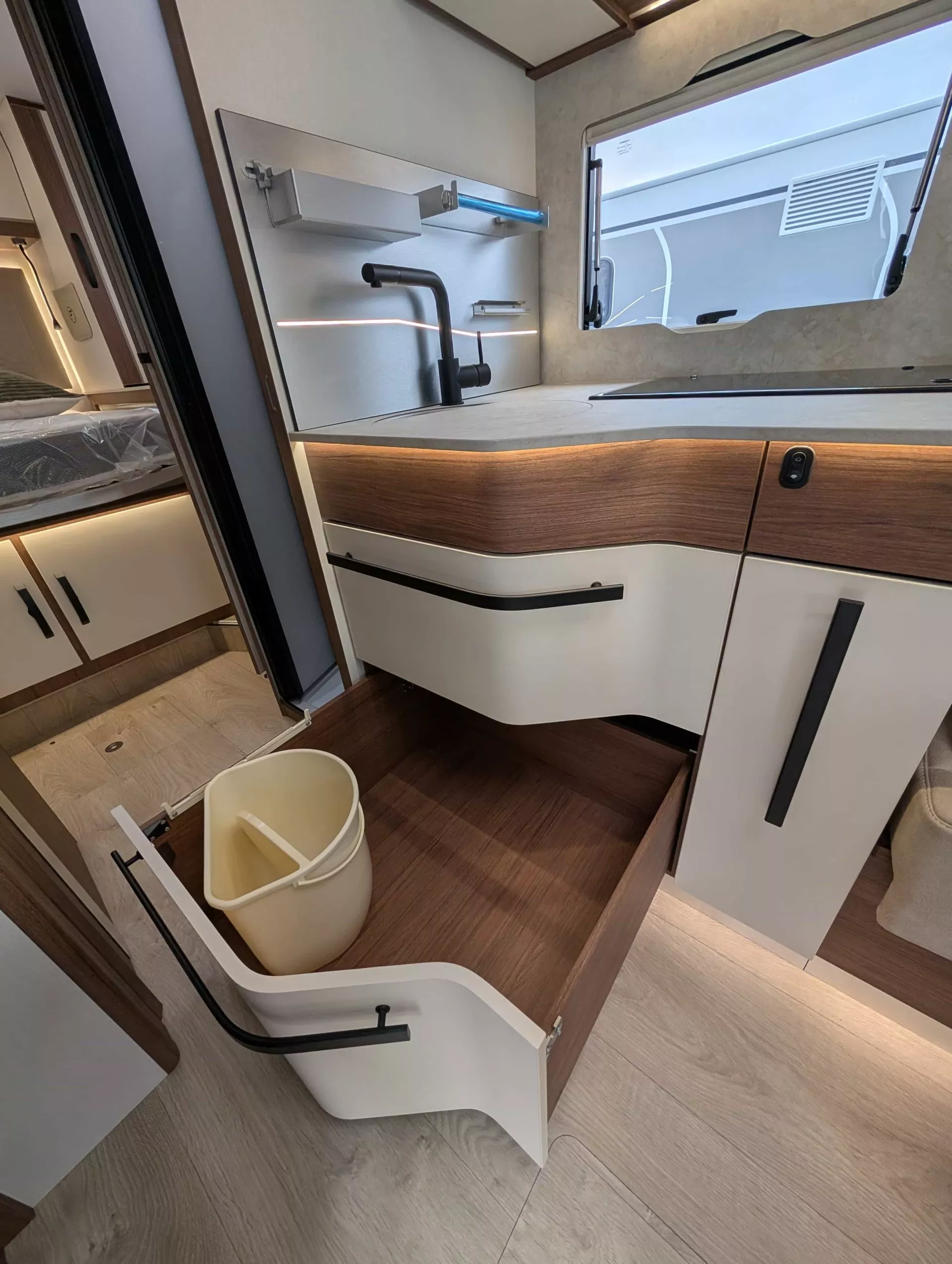 Cuisine moderne de camping-car avec évier, tiroir ouvert et poubelle intégrée