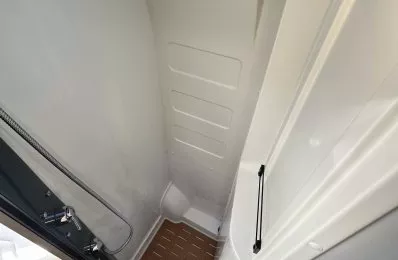 Douche compacte avec sol en bois dans un camping-car moderne.