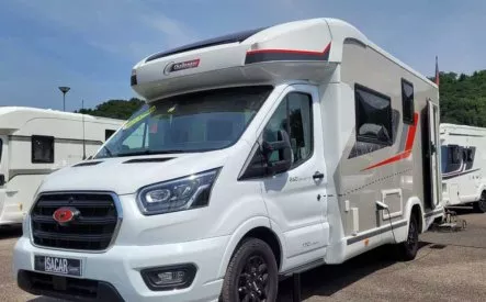 Camping-car Challenger stationné sur un parking sous un ciel bleu.
