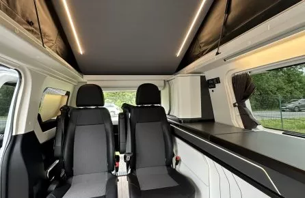 Intérieur d'un van aménagé avec sièges pivotants et éclairage LED