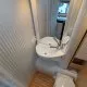 Salle de bain compacte avec lavabo, miroir et toilettes dans un camping-car moderne.