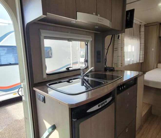 Cuisine compacte de caravane avec évier, plaques de cuisson et réfrigérateur intégré.