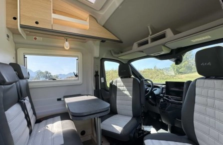 Intérieur d'un camping-car moderne avec sièges et table, vue sur la nature