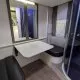 Intérieur d'une caravane avec table pliante, banquette et cabine de douche.