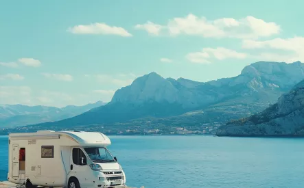 Camping-car stationné au bord d'une falaise avec vue sur la mer et montagnes