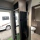 Intérieur d'une caravane moderne avec salle de bain et réfrigérateur visible.