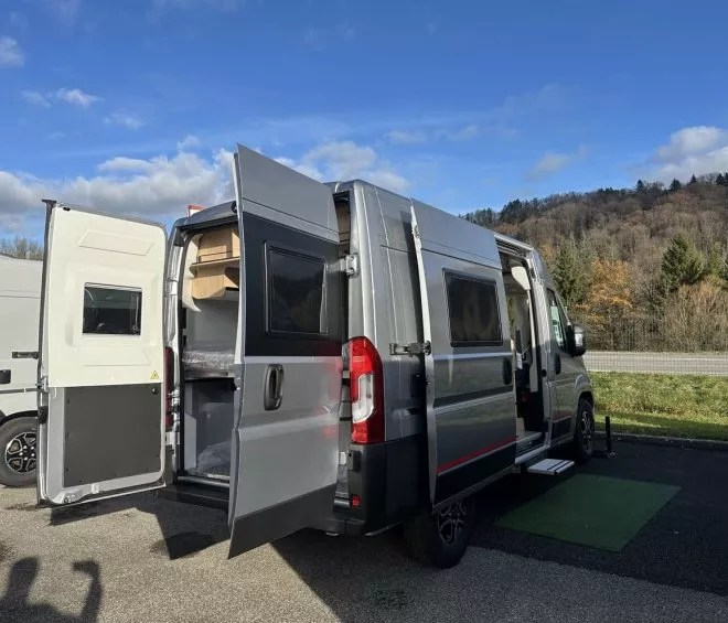 Fourgon aménagé stationné avec portes ouvertes, vue sur l'intérieur