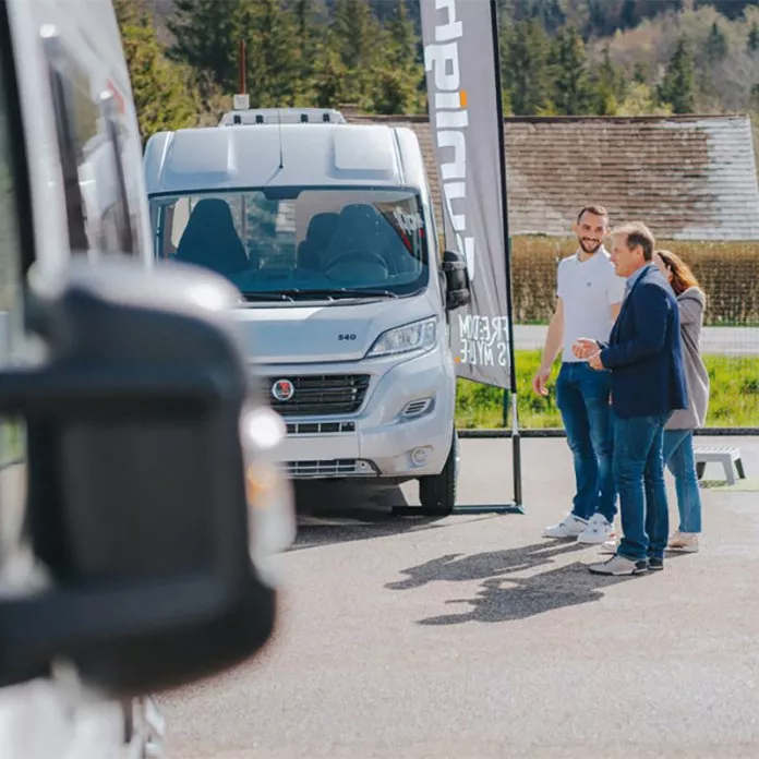 Présentation d'un camping-car devant des visiteurs lors d'un événement en plein air.