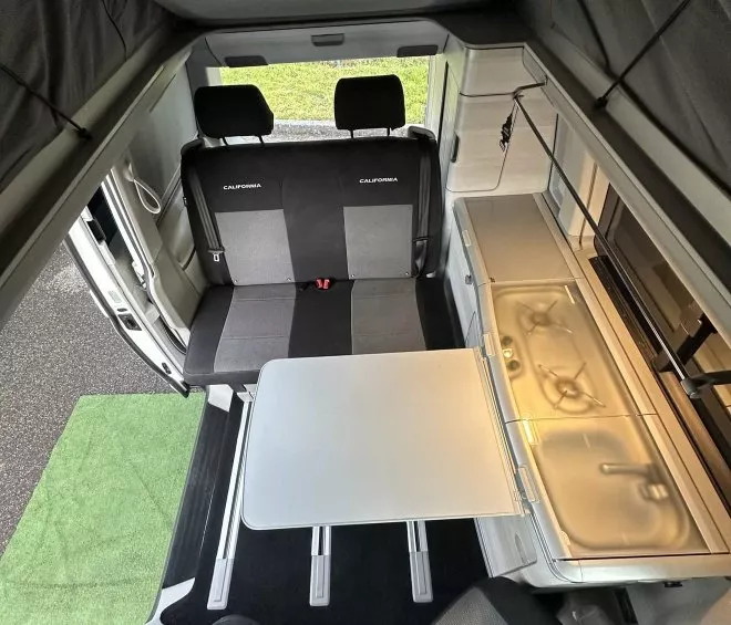 Intérieur d'un van aménagé avec table, sièges et kitchenette