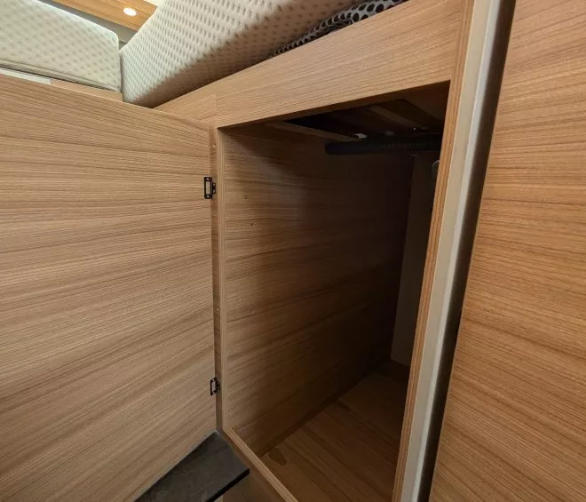 Placard en bois ouvert sous un lit dans un espace de rangement compact.