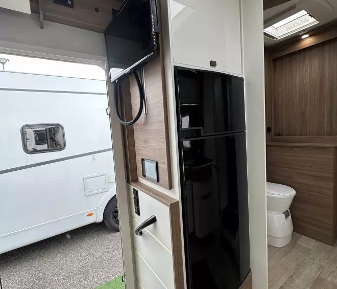 Intérieur d'un camping-car moderne avec télévision et salle de bain visible.