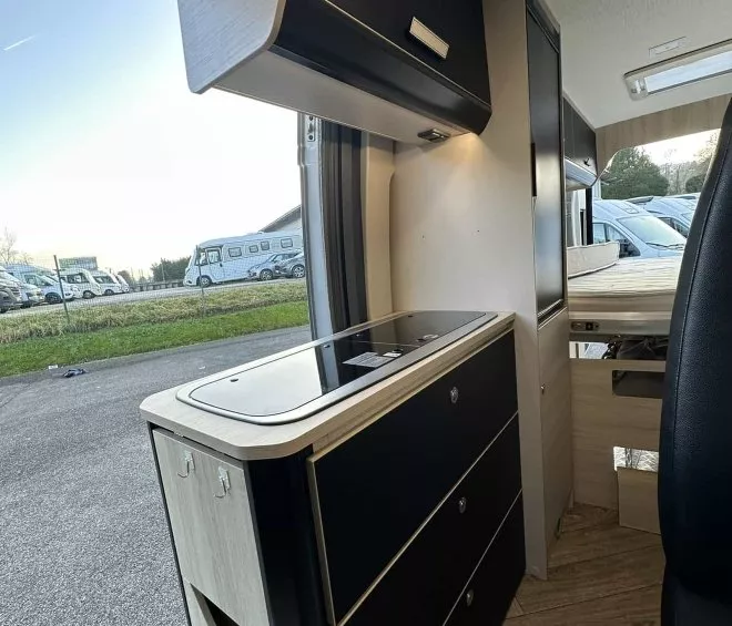 Intérieur moderne d'un camping-car avec cuisine équipée et rangements.