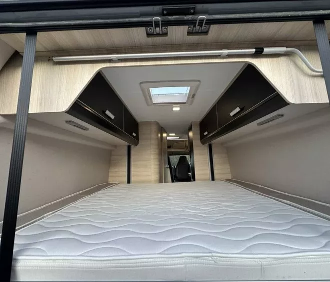 Intérieur d'un camping-car avec lit et rangements intégrés, éclairage LED