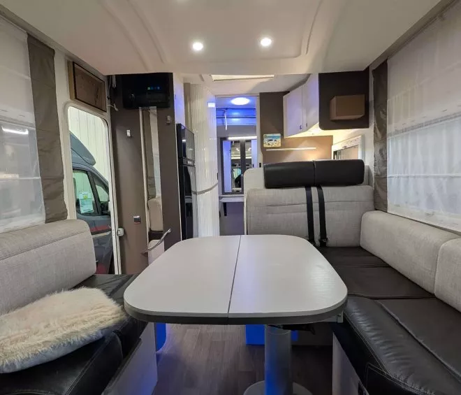 Intérieur d'un camping-car moderne avec table et banquettes grises