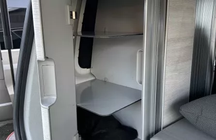 Rangement intérieur d'un van aménagé avec étagères et porte ouverte.