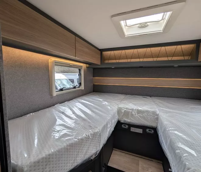 Intérieur d'un camping-car avec lits jumeaux et rangement en bois.