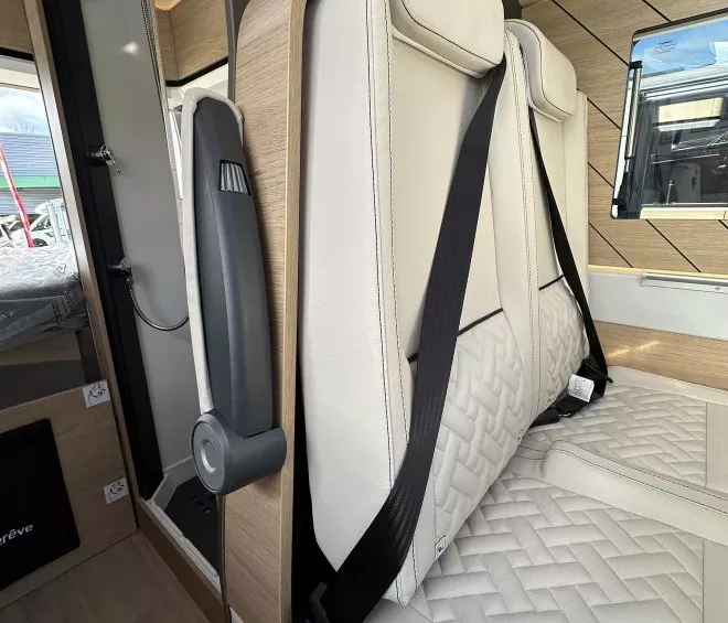Siège de camping-car avec ceinture de sécurité et revêtement en cuir beige.