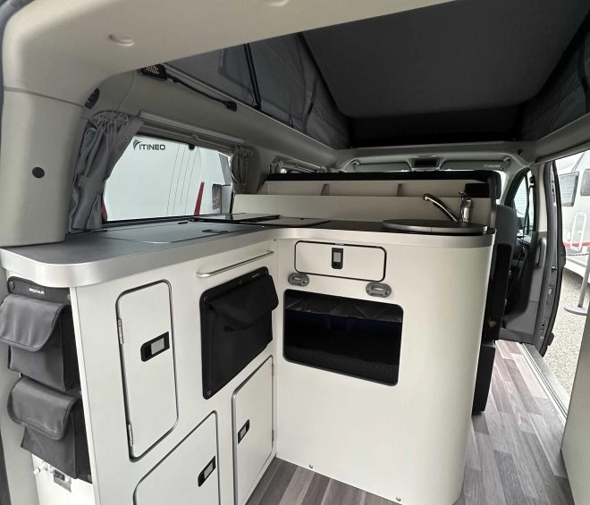 Intérieur d'un van aménagé avec cuisine compacte et rangements intégrés.