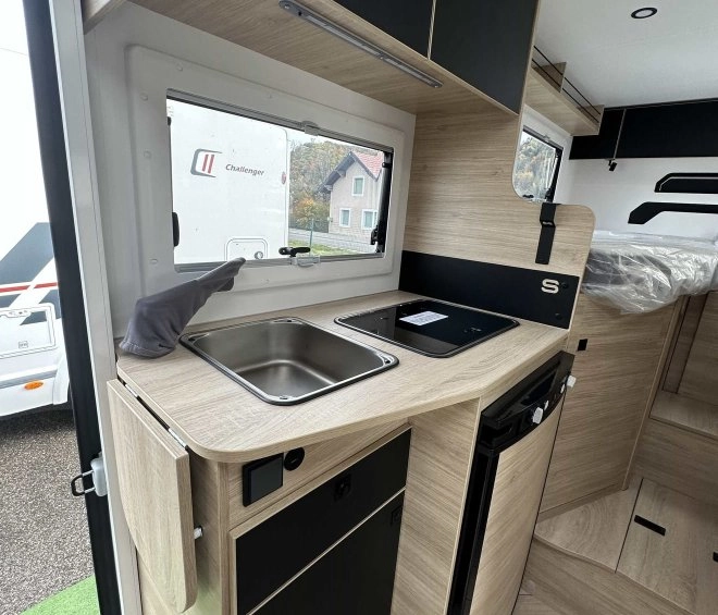 Cuisine compacte de camping-car avec évier, plaque de cuisson et réfrigérateur intégré.