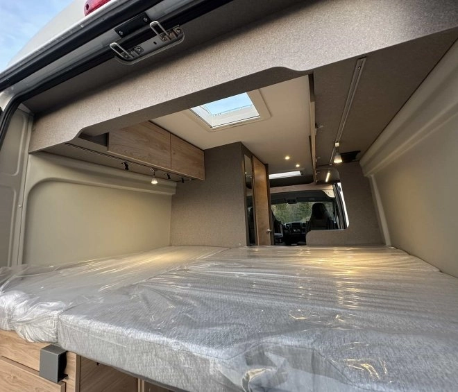 Intérieur d'un van aménagé avec lit et rangements en bois
