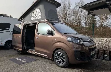 Van aménagé avec toit relevable sur un parking, modèle Crosscamp.