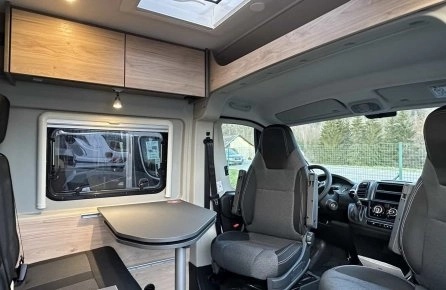 Intérieur d'un camping-car moderne avec sièges et table pliante.