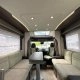 Intérieur spacieux d'un camping-car moderne avec sièges et table.