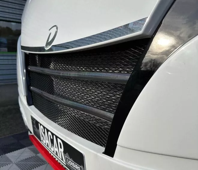 Gros plan sur la calandre d'un véhicule blanc avec logo et plaque Isacar Loisirs.