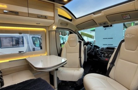 Intérieur d'un camping-car moderne avec sièges en cuir et table pliante.