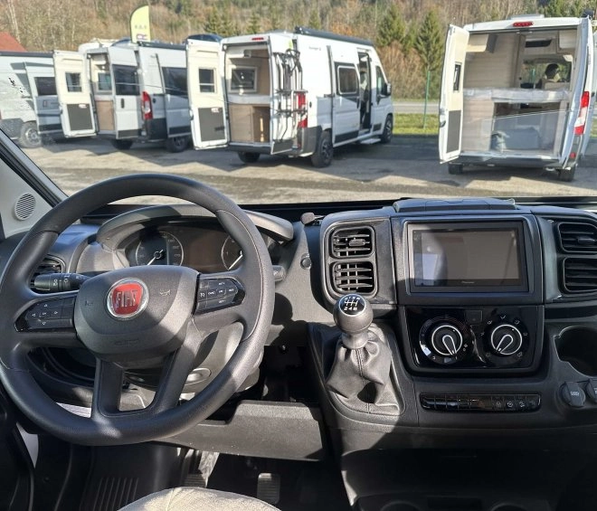 Intérieur d'un camping-car Fiat avec vue sur d'autres véhicules stationnés
