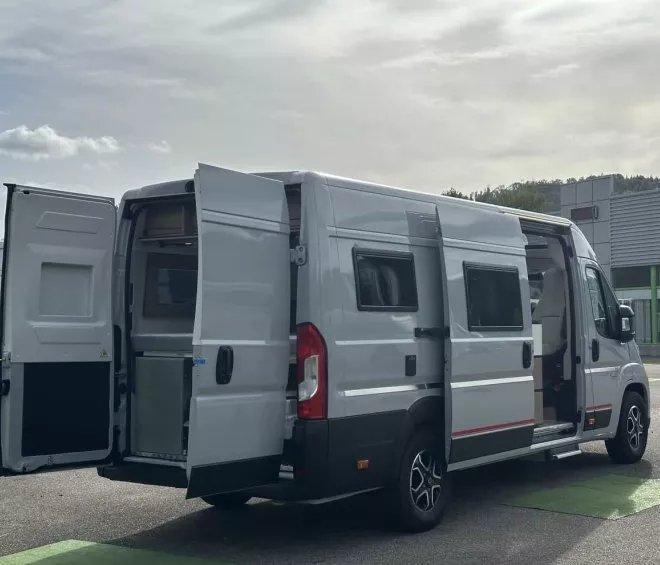 Fourgon aménagé stationné avec portes ouvertes sur un parking