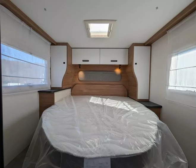 Intérieur d'une caravane avec lit double et rangements en bois clair