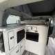 Intérieur d'un van aménagé avec cuisine compacte et rangements intégrés.