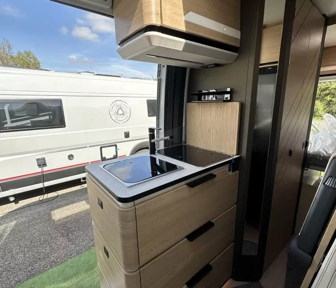 Intérieur moderne d'un camping-car avec cuisine équipée et rangements en bois clair.