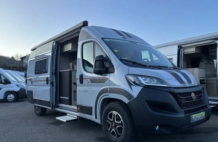 Camping-car gris stationné sur un parking, porte latérale ouverte