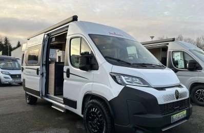 Camping-car blanc Dethleffs avec porte ouverte sur un parking