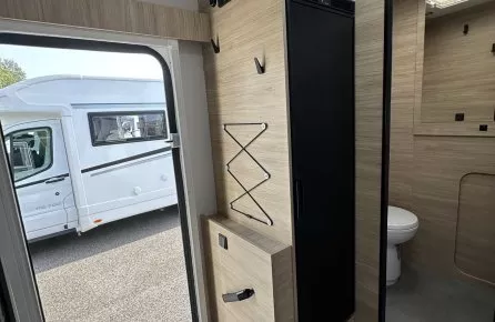 Intérieur d'un camping-car moderne avec salle de bain et mobilier en bois clair.