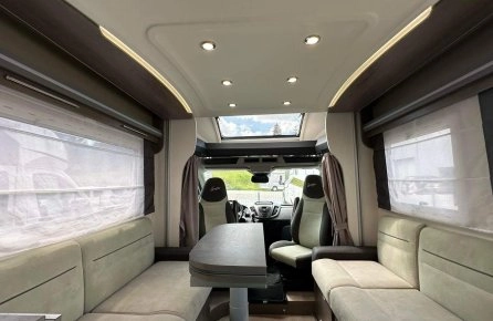 Intérieur spacieux d'un camping-car moderne avec sièges et table.