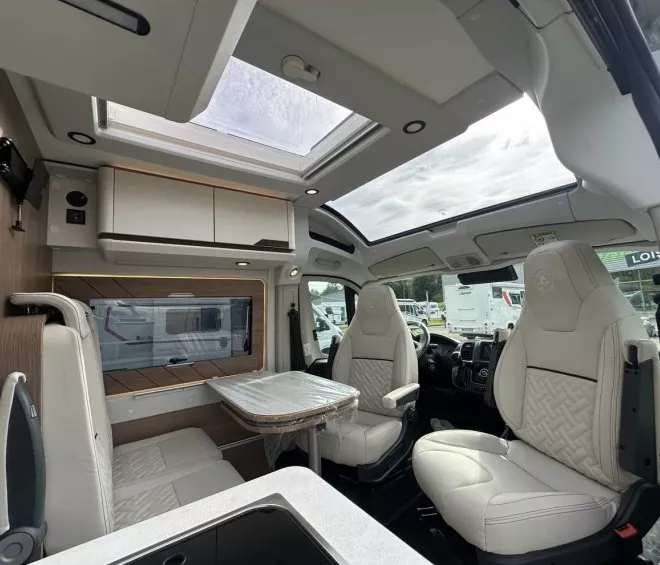 Intérieur d'un camping-car moderne avec sièges en cuir et toit panoramique.