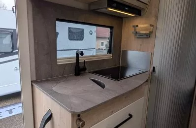 Cuisine moderne de camping-car avec évier et plaque de cuisson intégrée.