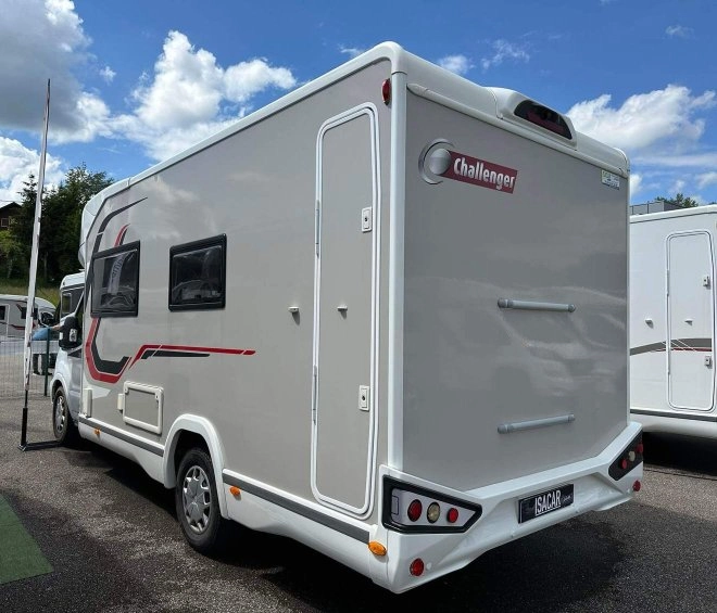 Camping-car Challenger stationné sur un parking sous un ciel bleu avec nuages