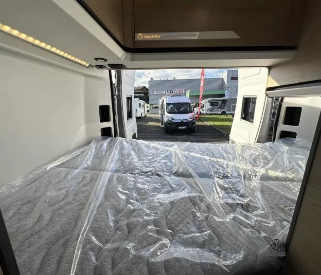 Intérieur d'un camping-car avec lit, vue sur concessionnaire