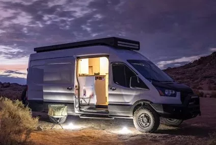 Van aménagé éclairé au crépuscule dans un paysage désertique