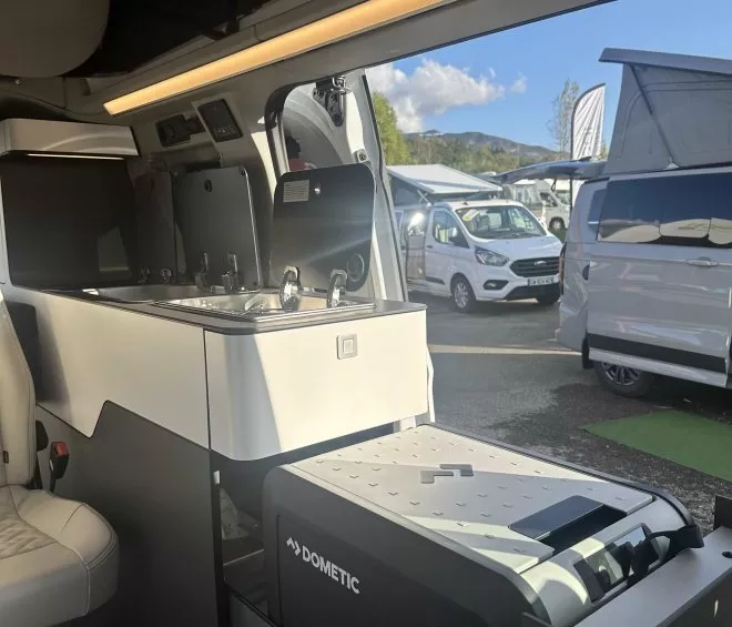 Intérieur d'un van aménagé avec cuisine et réfrigérateur Dometic CFX, stationné en extérieur.