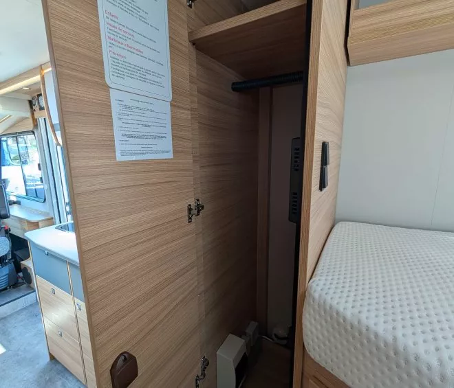 Intérieur d'un placard en bois dans un camping-car moderne avec lit et cuisine visibles.
